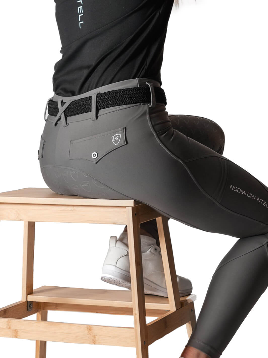 Ridbyxor Montana - Modellen sitter på en pall för att visa hur byxorna ser ut när man sitter ner. Byxorna är ljusgrå med vita loggor på både bakficka samt höger byxben. 
